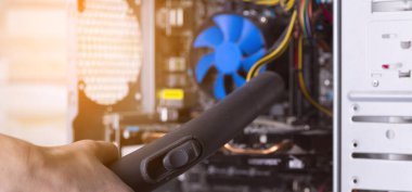 Bir masaüstü bilgisayarının sistem birimini elektrikli süpürgeyle tozdan temizlemek.
