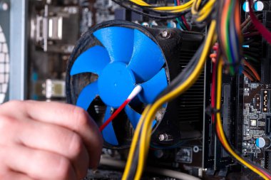 Eski bir bilgisayarın iç parçaları. Tozlu ana kart, video kartı ve vantilatör. Usta bilgisayarın soğutucusunu tozdan temizliyor. Kırık PC.