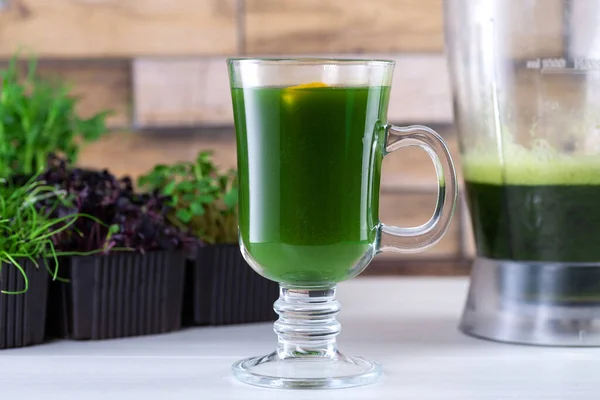 Jugo microverde en la mesa de la cocina. Micro greens en una licuadora. Haz un batido microverde en casa. Alimento sano y ecológico — Foto de Stock