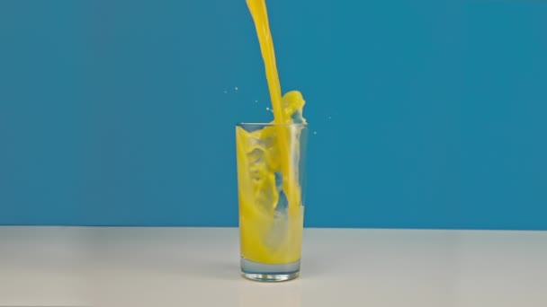 Langzame beweging van sinaasappelsap dat in een glas stroomt — Stockvideo