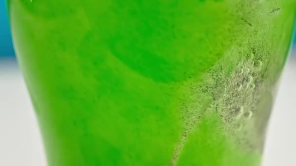 Burbujas de cámara lenta se levantan en un vaso de limonada verde con hielo de cerca — Vídeos de Stock