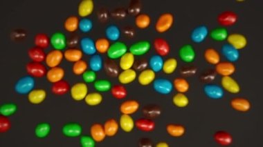 Yavaş çekim çok renkli M & M 'ler siyah arkaplanda uçuyor