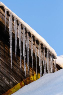 Keskin buz saçakları ve çatıdan sarkan erimiş kar.