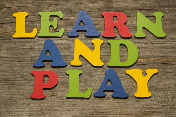 Aprender y jugar (letras de colores sobre un fondo de madera ) — Foto de Stock