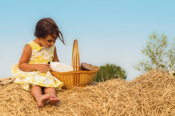 Menina sentada no palheiro com uma cesta de comida saudável — Fotografia de Stock