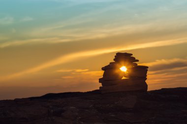 Close-up of Inukshuk  stones on ocean shore at sunset