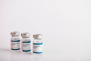 Tıbbi profesyonellere ve risk altındaki insanlara SARS-CoV-2 aşısı tedavisi için beyaz arka planlı üç Covid-19 aşı şişesi. Boşluğu kopyala.