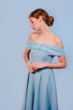 Mavi elbiseli güzel, şık bir kızın orta boy fotoğrafı. Mavi arka planda izole edilmiş. Kopyalama alanı tasarla.