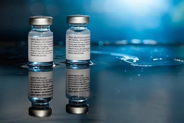 San Sebastian, Gipuzkoa, İspanya; 24 Nisan 2021. Kullanım talimatlarıyla birlikte iki şişe Pfizer-Biyotek Covid-19 aşısı. Yakın çekim, seçici odaklanma. Mavi ışık. Mavi arkaplan.