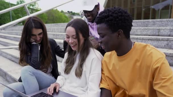 Czterech Studentów Dobrze Się Bawiących Siedząc Schodach Patrząc Laptop Kampusie — Wideo stockowe