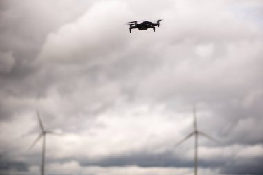 Kara İHA Sürdürülebilir Rüzgar Türbinlerinin Epik Bulutlu Tarlasında Uçuyor.