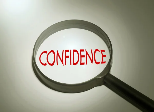 Magnifying glass with the word confidence. Searching confidence — Stock Photo, Image