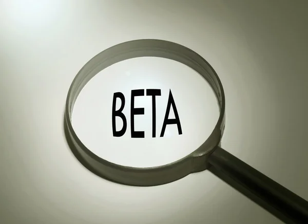 Magnifying glass with the word beta. Searching beta — Stock Photo, Image