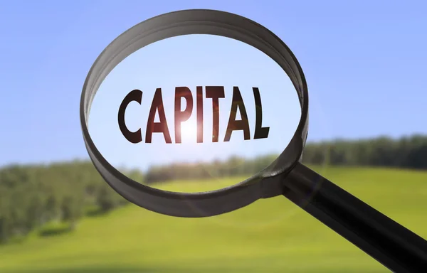 Ampliação com a palavra capital sobre fundo natureza turva. Conceito de capital à procura — Fotografia de Stock