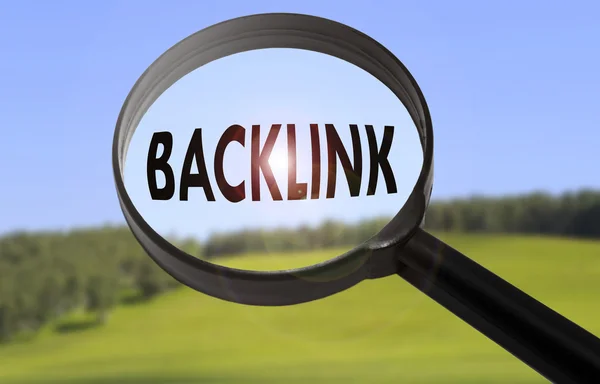 Vergrootglas met het woord backlink op vage natuur achtergrond. Zoeken backlink concept — Stockfoto