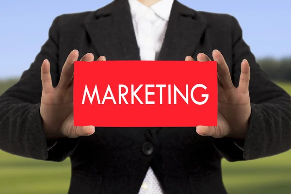 Businesswoman in a black jacket shows a card with the inscription marketing. Selective focus. — Stock Photo, Image