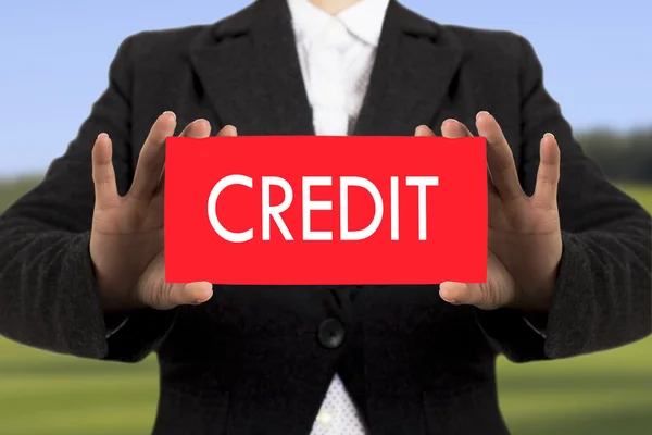 Businesswoman in a black jacket shows a card with the inscription credit. Selective focus. — Stock Photo, Image