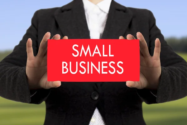 Businesswoman in a black jacket shows a card with the inscription small business. Selective focus. — Stock Photo, Image