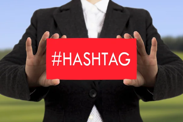 Geschäftsfrau im schwarzen Sakko zeigt eine Karte mit der Aufschrift Hashtag. Selektiver Fokus — Stockfoto