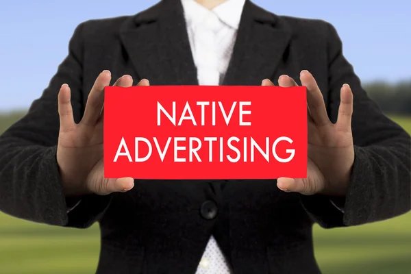 Geschäftsfrau in schwarzem Sakko zeigt eine Karte mit der Aufschrift "Native Werbung". Selektiver Fokus. — Stockfoto