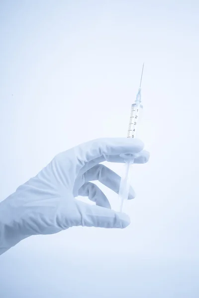 Gloved hand holding a medical syringe — Stock Photo, Image