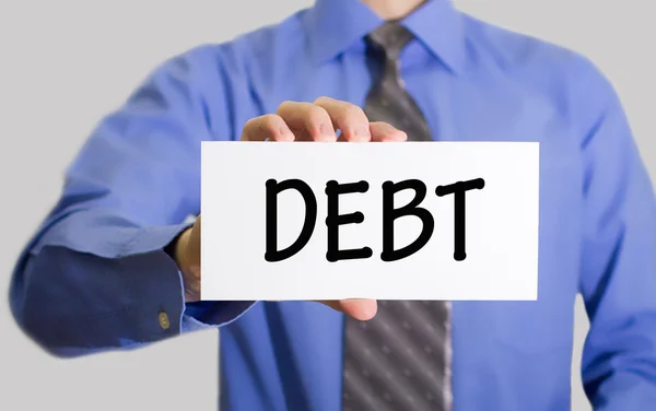 Businessman in blue shirt and gray tie shows a card with the inscription debt.