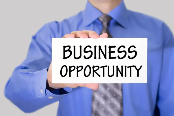 Businessman in blue shirt and gray tie shows a card with the inscription business opportunity — Stock Photo, Image