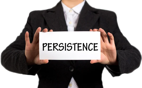 Businesswoman in a black jacket and a white shirt shows a card with the inscription persistence — Stock Photo, Image