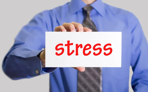 Businessman in blue shirt and gray tie shows a card with the inscription stress — Stok fotoğraf