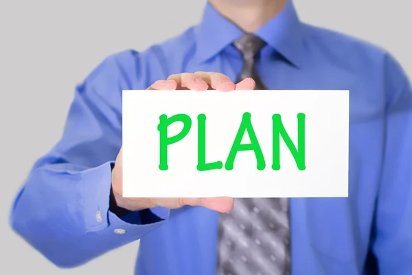 Empresario en camisa azul y corbata gris muestra una tarjeta con el plan de inscripción — Foto de Stock