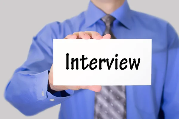 Biznesmen w niebieska koszula i krawat szary pokazuje kartę z napisem wywiad — Zdjęcie stockowe