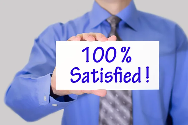 Homme d'affaires en chemise bleue et cravate grise montre une carte avec l'inscription 100 satisfait — Photo