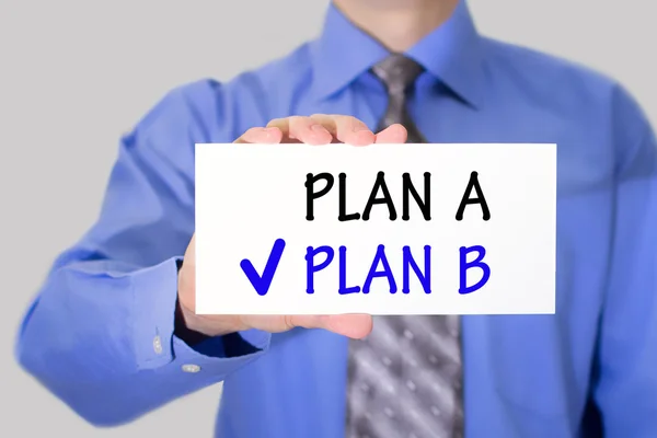 Businessman in blue shirt and gray tie shows a card with the inscription plan b — Stock Photo, Image