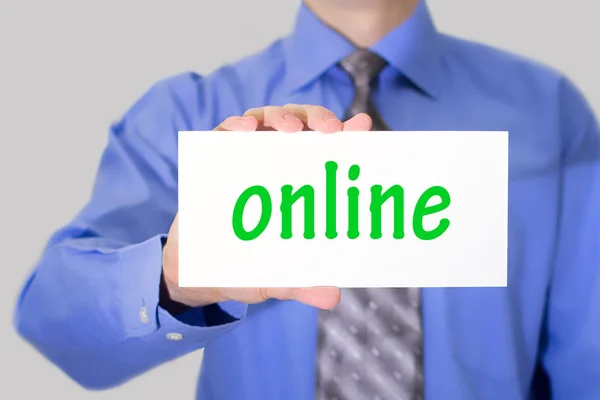 Businessman in blue shirt and gray tie shows a card with the inscription online. — Stock Photo, Image