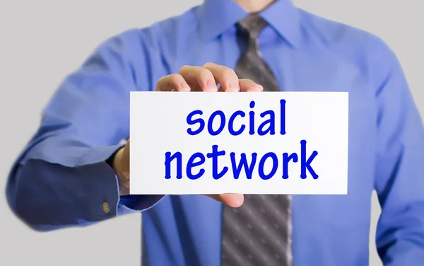 Homme d'affaires en chemise bleue et cravate grise montre une carte avec l'inscription réseau social . — Photo