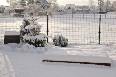 Plastik beste kutusu ve karla kaplı, arka bahçedeki kış mevsimi sahnesi.