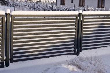 Kışın karla kaplı modern grafit metal çitler.