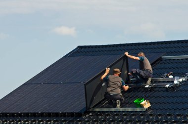 Özel bir evin metal çatısına yeni siyah güneş panelleri kurmak. Ekoloji, yenilenebilir enerji ve yeşil sürdürülebilir güç kaynağı soyut.