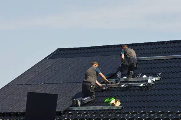 Özel bir evin metal çatısına yeni siyah güneş panelleri kurmak. Ekoloji, yenilenebilir enerji ve yeşil sürdürülebilir güç kaynağı soyut.