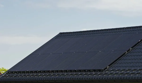 Özel bir evin metal çatısına yeni siyah güneş panelleri kurmak. Ekoloji, yenilenebilir enerji ve yeşil sürdürülebilir güç kaynağı soyut.