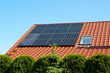 Özel evin arka planındaki kırmızı teneke çatıdaki yeni güneş panelleri. Yenilenebilir yeşil enerji soyut.