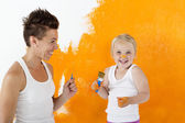 Mutter und Tochter malen zu Hause eine Wand