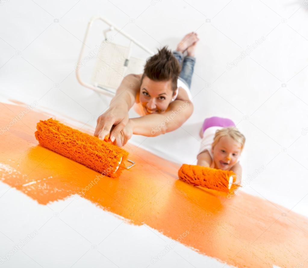 Mother and daughter painting a wall at home