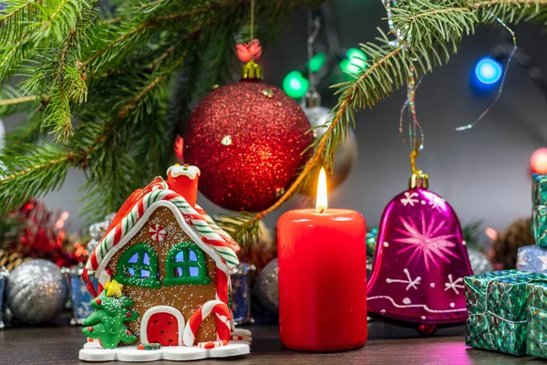 Noel ağacı, Noel ağacının dalında kırmızı toplar, hediyeler ve çelenklerle süslenir. Kırmızı bir mum ve renkli bir ev şeklinde Noel kurabiyesi ile Noel süslemesi..