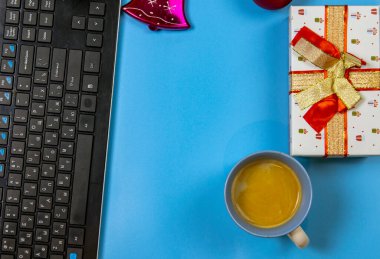 Masada kozalaklı dallar, Noel topları, bilgisayar ve bir hediye kutusu, ışıl ışıl Noel topları. Evden internetten hediye sipariş etmek. Metnin için yer.