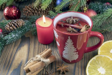 Noel mumlu bir masa manzarası, sıcak sıcak sıcak şarap, köknar dallı ahşap bir kırsal masa üzerinde baharatlar ve meyveler. Geleneksel Noel içkisi.