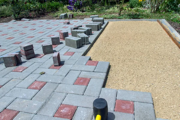 Laying paving stones on a garden path. Laying gray concrete paving slabs in the yard on a flat sandy foundation