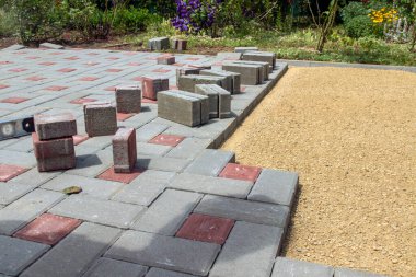 Bahçe yolunda taş döşemek. Düz kumlu bir temele gri beton döşeme döşeme döşemesi