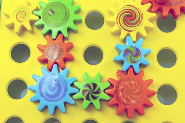 Colored plastic gears on an orange background, top view. Communication and teamwork concept