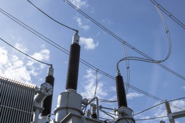 Mavi gökyüzüne karşı yüksek voltajlı trafo. Elektrik akımı yeniden dağıtım alt istasyonu